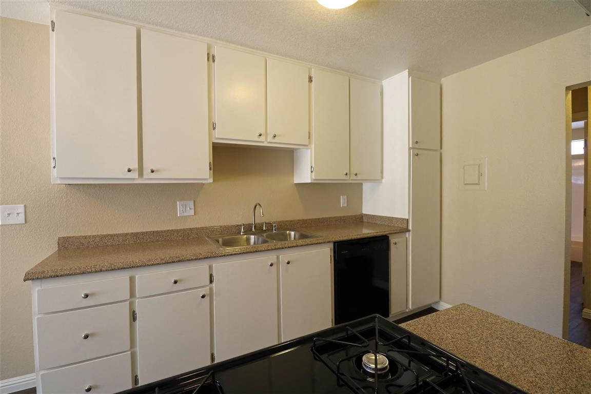 A kitchen with a black stove top and white cabinets.